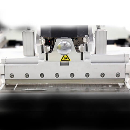 Screen printing machine with squeegee assembly and yellow warning label.