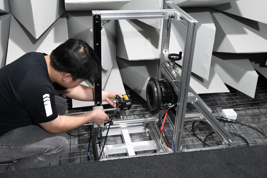 Engineer conducting audio speaker testing with precision measurement equipment in anechoic chamber