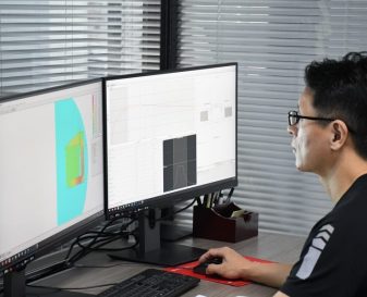 Engineer simulation Engineer analyzing audio simulation data on dual monitor workstation